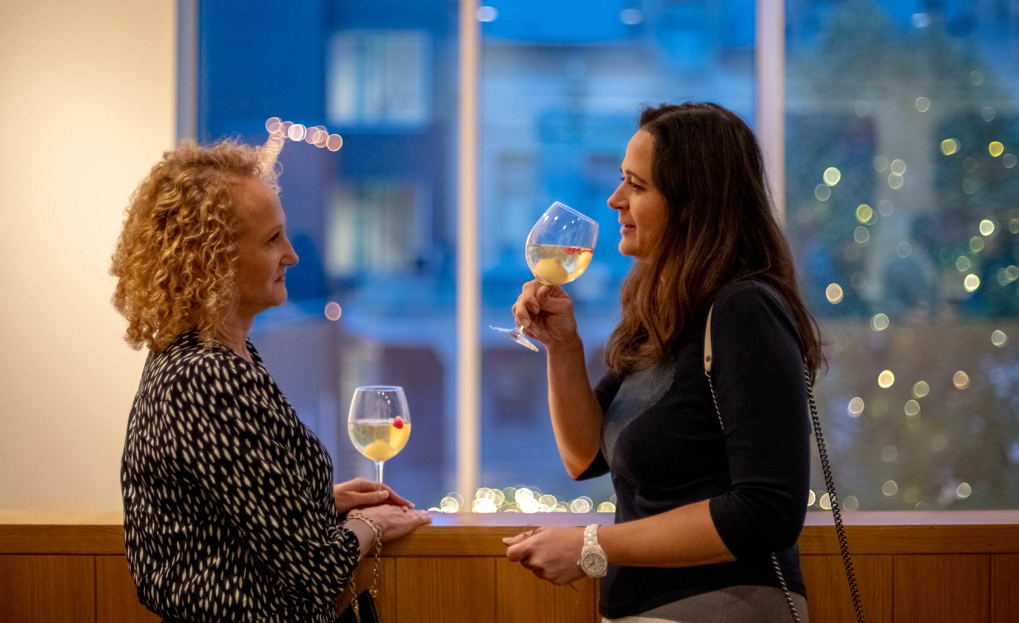 two women enjoying drinks during an event cocktail hour